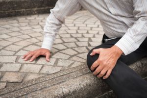 A man clutching his knee in pain after falling