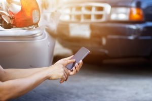 A driver involved in a car accident calls their insurance provider at the accident scene