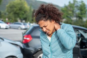 Woman holds neck in pain due to whiplash following a car accident