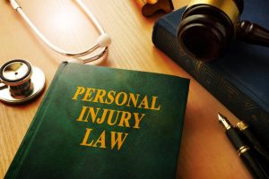 A green book on a desk. The words 'personal injury law' are written in gold text on the front cover.