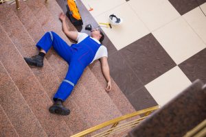 A worker lying on the floor with injuries from falling down stairs