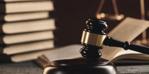 A wooden gavel and some books on a desk.