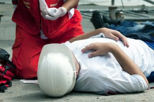 An injured worker lying on the floor and being given first aid.