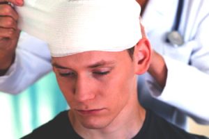 A doctor wraps bandages around a man's head following a Head injury at work