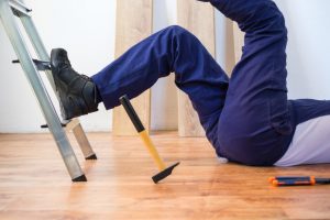 A man falling off a ladder and suffering a workplace injury.