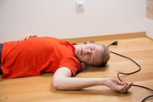 Injured man lying on the floor after tripping over a trailing cable hazard. 