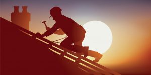 Sunset silhouette of a roofer working while attached to a roof with safety ropes.