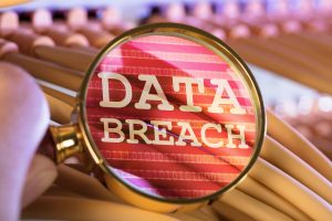 A magnifying glass zooming on on the words 'data breach'.