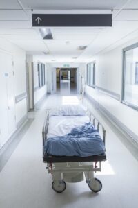 An empty hospital bed in the middle of an empty aisle.
