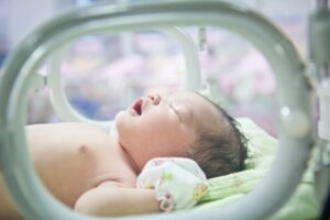 A newborn baby cries in an incubator