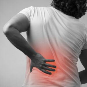 A black and white image of a man clutching his back in pain, where it radiates red