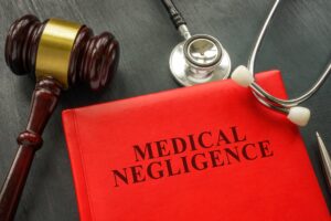 Medical negligence written on a red folder with a stethoscope and judge's gavel hammer