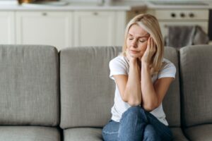 Woman Sat On Sofa Suffering Emotional Health Problems. 