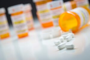 A group of orange pill bottles with one bottle spilling white tablets onto the table.