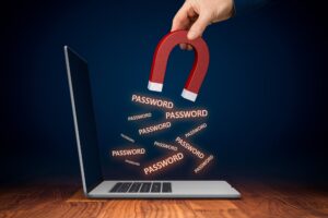 A magnet being held over a laptop extracting passwords to illustrate data protection breaches.