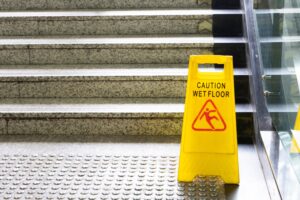 A yellow wet floor sign sits at the bottom of a public staircase