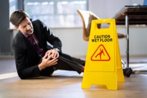 A man with a knee injury and wet floor sign. 