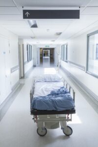 A hospital bed in the middle of a corridor creating a trip or fall hazard.