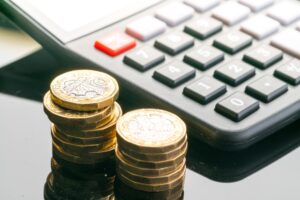 Two piles of coins and a calculator, which represent data breach compensation.