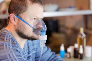 A close-up image of a person wearing an oxygen mask over their mouth and nose.
