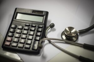 A calculator and a stethoscope together on a table to represent compensation in meningitis negligence claims.