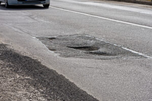 A pothole is visible on the road, which could be grounds for a motorcycle accident injury claim. 