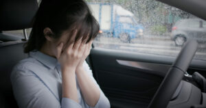 A woman cries in the driver's seat of her car.