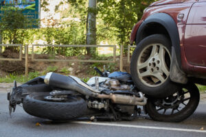 A car and motorbike both show damage after a collision on the road.