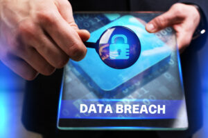 Person holding a magnifiying glass over table displying a padlock and the words 'data breach'. Lost medical data could give rise to a personal data breach claim
