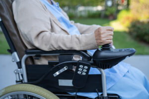 An elderly person wearing a hospital gown sitting in an electric wheel chair after negligent medical treatment resulted in their illness becoming terminal