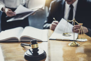 Two data breach solicitors sit at a desk completing paperwork. There is a gavel and scales of justice in the foreground