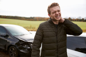 A man holding his beck in pain after a car accident.