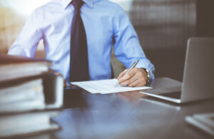 A solicitor sat at a desk with a notepad and laptop calculating an NHS data breach compensation figure for his client.