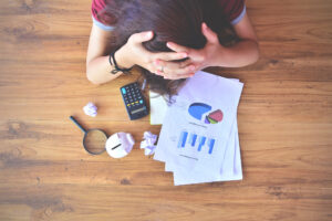 A woman holds her head with a calculator