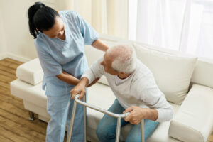 A nurse helps an elderly patient stand up.