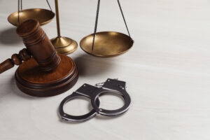 A set of justice scales, a judge's gavel and a pair of handcuffs on a table
