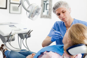 A dentist checks a young woman's teeth in a clinic