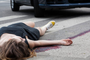 A pedestrian hit by a car lays in the road.