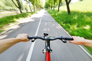 A person riding their red bike on a tree-lined path.
