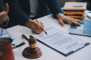 A lorry accident claims solicitor sat at a desk signing a document.