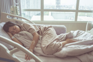 A sick pregnant woman lays on her side in pain in a hospital bed. 