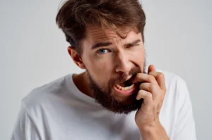 A man holding his jaw in discomfort.