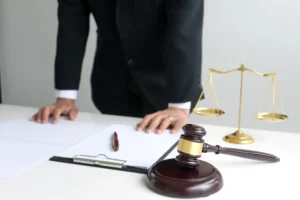 A specialist solicitor leans on a table with a clipboard, gavel and scales